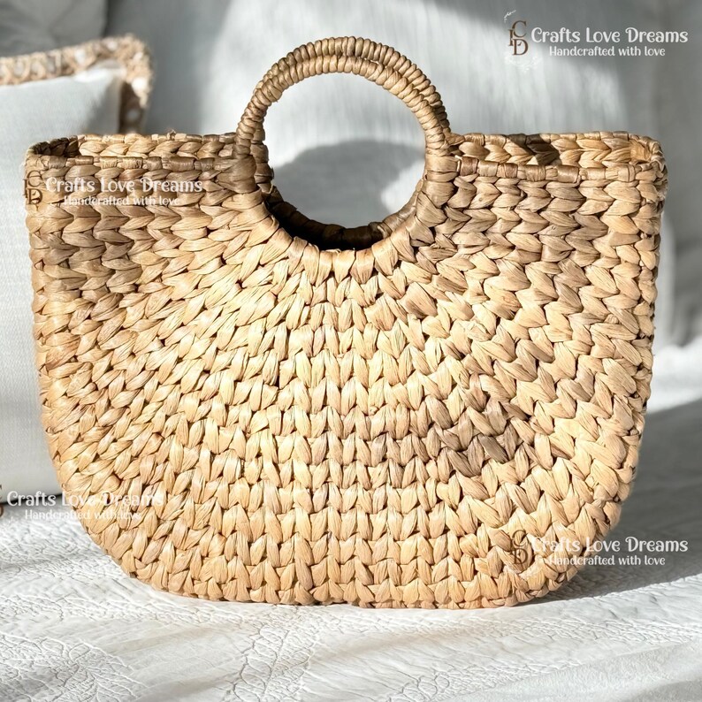 A woven straw handbag with a round handle, displayed on a white surface.
