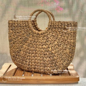 A woven handbag with a round handle, displayed on a wooden surface.