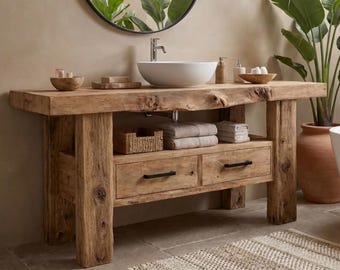 Op de afbeelding: Een badkamermeubel gemaakt van lichtbruin gerecycled hout met een natuurlijke rand, voorzien van twee lades met zwarte metalen handgrepen, een open plank met gevouwen handdoeken en een gevlochten mand, en een witte keramische waskom.