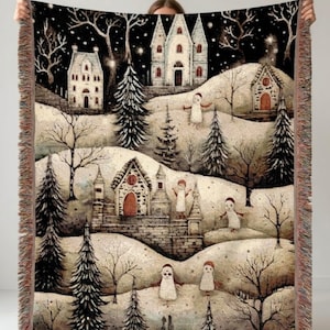 Könnte beinhalten: Eine gewebte Wohndecke mit einer Winterszene aus weißen Gebäuden, verschneiten Hügeln, Nadelbäumen und kleinen geisterhaften Figuren. Das Design zeigt einen dunklen Nachthimmel mit Sternen und einen dekorativen Fransenrand an den Seiten.
