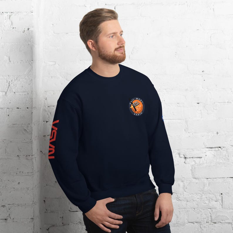 May include: Navy blue sweatshirt with the word "NASA" printed in orange on the left sleeve. The right chest features a circular graphic with the words "Hail Mary Earth" and a stylized planet.