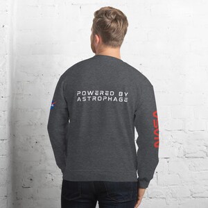 May include: Dark gray sweatshirt with the text "POWERED BY ASTROPHAGE" in white across the back. The NASA logo is on the left sleeve, and the word "NASA" is printed vertically in red on the right sleeve.