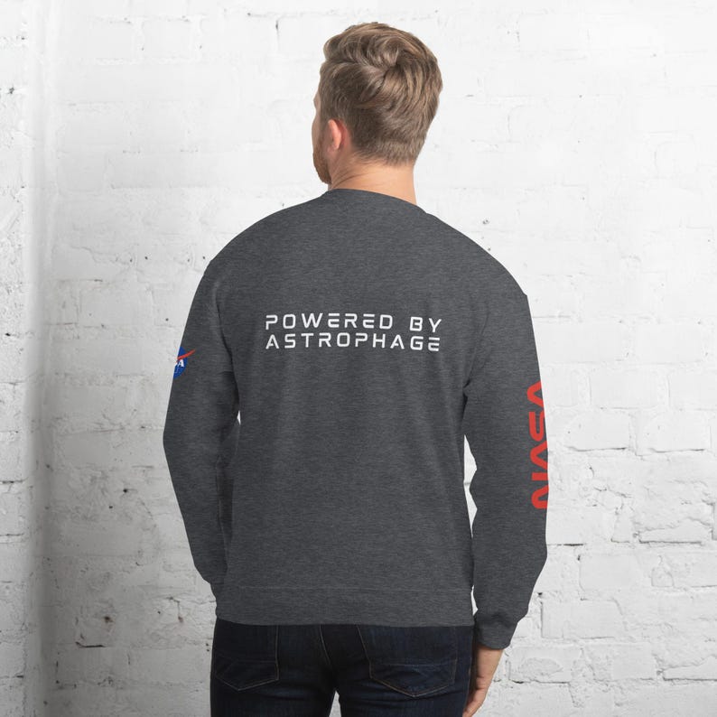 May include: Dark gray sweatshirt with the text "POWERED BY ASTROPHAGE" in white across the back. The NASA logo is on the left sleeve, and the word "NASA" is printed vertically in red on the right sleeve.
