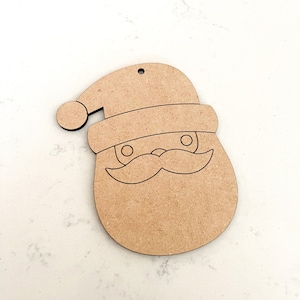 May include: Unpainted wooden ornament shaped like Santa Claus's face with a hat, eyes, mustache, and beard.