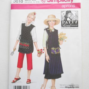 May include: Simplicity apron sewing pattern packet. The packet features two apron designs, one with a polka dot pattern and the other with vertical stripes. The packet includes the text "Simplicity aprons" and "PATTY Reed DESIGNS".
