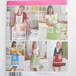 May include: Simplicity sewing pattern 2980 featuring apron designs. The pattern includes various apron styles with different colors and patterns, including red, white, blue, and green. The pattern also includes the text "Kimberly Einmo".