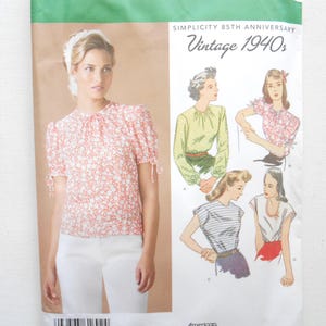 May include: Simplicity sewing pattern 1692 for a 1940s style blouse. The envelope features a photograph of a person wearing a floral print top with puff sleeves and tie details, alongside illustrations of four different blouse variations.
