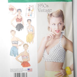 May include: A Simplicity 1426 R5 sewing pattern envelope for 1950s vintage style halter tops. The package features illustrations of various top designs, including polka dot and solid patterns, with U.S. sizes 14-22 printed on the top front.