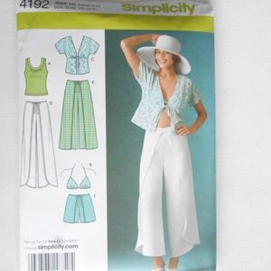 May include: Simplicity sewing pattern 4192. The pattern includes designs for a top, skirt, shorts, and a bikini top. The cover features a woman wearing a white outfit with a patterned top and wide-leg pants. The pattern size is HS 6,8,10,12,14.