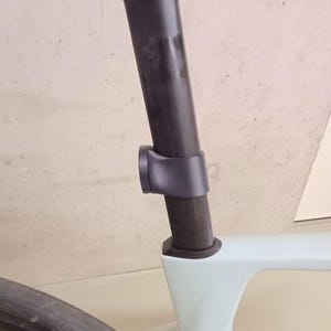 Può includere: Primo piano di un telaio di bicicletta con reggisella nero e morsetto grigio. Il telaio è azzurro. Lo pneumatico anteriore è visibile in basso a sinistra.