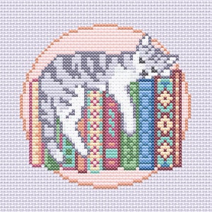 Könnte beinhalten: Eine weiße Katze, die sich neben einem Stapel bunter Bücher zusammengerollt hat. Die Bücher haben verschiedene Muster und Designs. Die Katze und die Bücher befinden sich in einem runden Rahmen mit einem pfirsichfarbenen Hintergrund.
