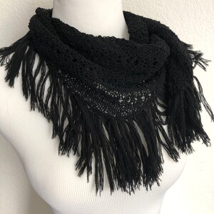 May include: Black crochet scarf with fringe. The scarf is made of a delicate, openwork pattern and has a long, flowing fringe.