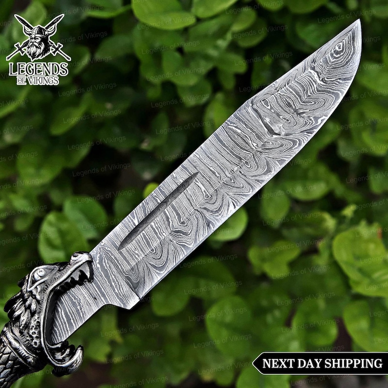 May include: A Damascus steel knife with a detailed blade pattern and a handle featuring a wolf's head design. The knife has a long, sharp blade and is set against a backdrop of green foliage. The text "Legends of Vikings" is visible.