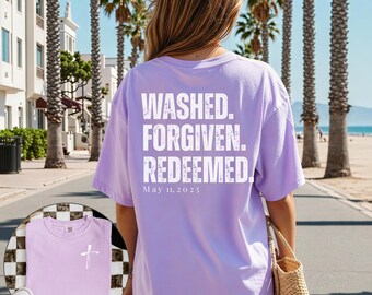 May include: A light purple t-shirt with the words "WASHED. FORGIVEN. REDEEMED." printed on the back in white. The date "May 11, 2025" is printed below. A smaller image shows the front of the shirt with a cross.