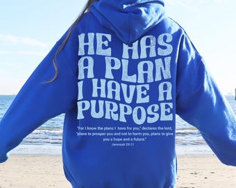 May include: Royal blue hoodie with the text "HE HAS A PLAN I HAVE A PURPOSE" in white. The back of the hoodie also features a quote from Jeremiah 29:11. The hoodie is a comfortable, casual garment.