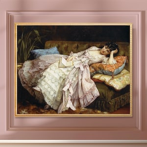 May include: A framed painting of a woman in a pink and white dress reclining on a sofa with pillows, holding a book. The artwork is in a gold frame against a pink wall. The woman rests her head on her hand.