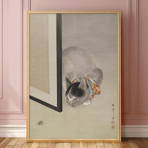 May include: Framed vintage Japanese artwork featuring a cat with a patterned collar, gazing intently at a spider. The cat has a black and white face and is set against a neutral background. The artwork is framed in a gold-colored frame.