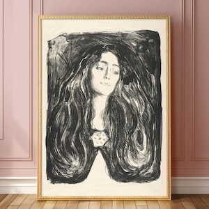 Pode incluir: Uma impressão emoldurada em preto e branco de uma mulher com cabelos longos e esvoaçantes. A obra de arte apresenta um retrato detalhado com uma expressão suave e um elemento decorativo no decote. A moldura é dourada.