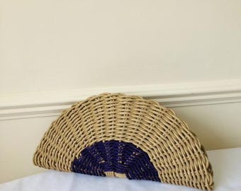May include: A half-circle woven wicker clutch bag with a purple accent.