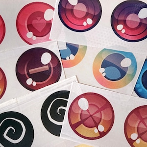 Peut inclure: Une collection de motifs circulaires colorés sur tissu blanc. Les motifs comprennent des enseignes de cartes à jouer, des signes plus et moins, et des motifs en spirale. La palette de couleurs varie du rouge et rose au bleu et violet, avec des reflets blancs.