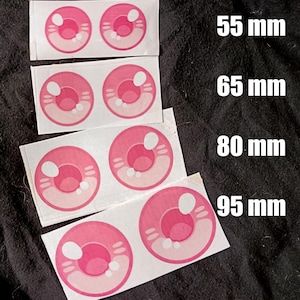Peut inclure: Patchs oculaires roses de style anime en quatre tailles : 55 mm, 65 mm, 80 mm et 95 mm. Chaque patch présente un iris rose avec des reflets blancs et un anneau extérieur rose clair. Les patchs sont sur du tissu blanc.