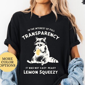 May include: Black t-shirt with a raccoon graphic and the text "In the interest of full transparency it was not easy peasy lemon squeezy".