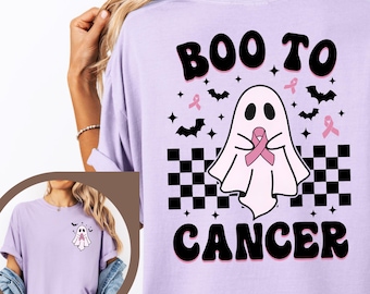 May include: An orchid-colored t-shirt featuring a back graphic of a white ghost holding a pink ribbon, surrounded by black bats and stars above a black and white checkered pattern, with the text BOO TO CANCER. A smaller version is on the front.