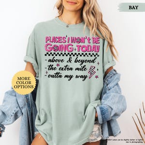 May include: A light green t-shirt with the text "PLACES I WON'T BE GOING TODAY" in pink and black. The shirt also features the phrases "above & beyond", "the extra mile", and "outta my way".
