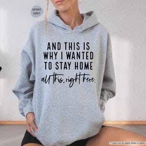 K&ouml;nnte beinhalten: Ein grauer Kapuzenpullover mit dem Text "AND THIS IS WHY I WANTED TO STAY HOME all this, right here." in Schwarz gedruckt.