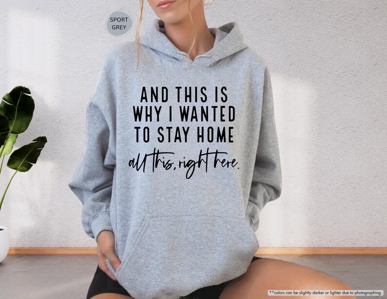 K&ouml;nnte beinhalten: Ein grauer Kapuzenpullover mit dem Text "AND THIS IS WHY I WANTED TO STAY HOME all this, right here." in Schwarz gedruckt.