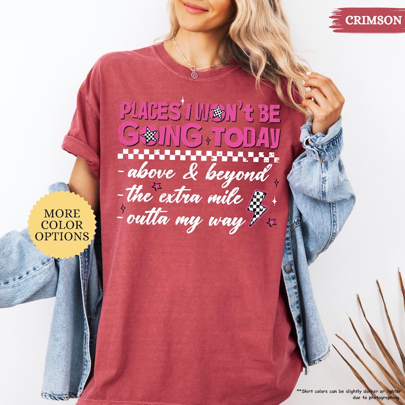 May include: Crimson-colored t-shirt with the text "PLACES I WON'T BE GOING TODAY" in pink and black. The shirt features additional text: "above & beyond", "the extra mile", and "outta my way". A "More Color Options" button is visible.