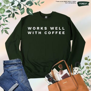 May include: A dark green sweatshirt with the text "WORKS WELL WITH COFFEE" in white lettering.