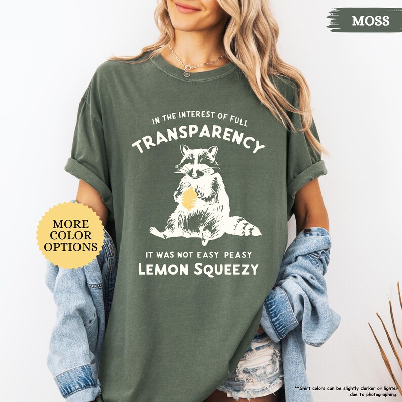 May include: A green t-shirt with a raccoon graphic and the text "In the interest of full transparency, it was not easy peasy lemon squeezy".
