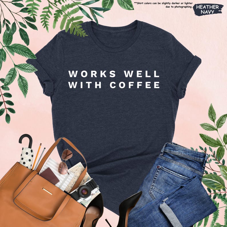 May include: A heather navy blue t-shirt with the text "WORKS WELL WITH COFFEE" in white lettering.