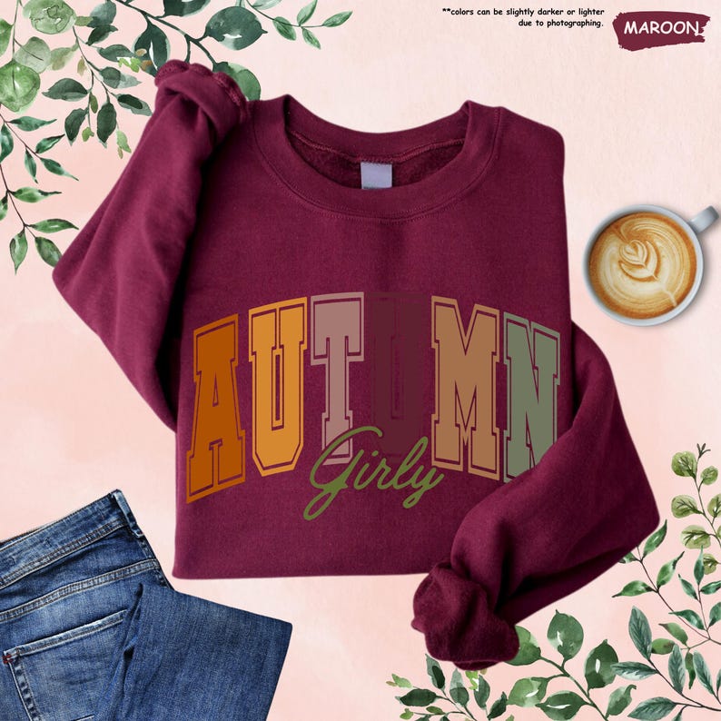a maroon shirt with the word autumn on it next to a pair of jeans and