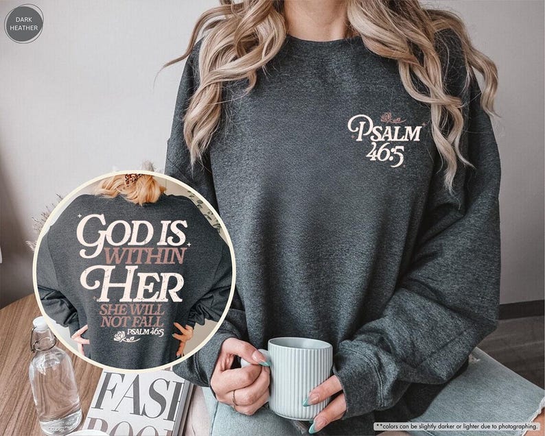 Puede incluir: Sudadera gris oscuro con el texto "Psalm 46:5" en escritura blanca en la parte delantera. La parte trasera de la sudadera presenta el texto "God is within her, she will not fall, Psalm 46:5" en una fuente estilizada.