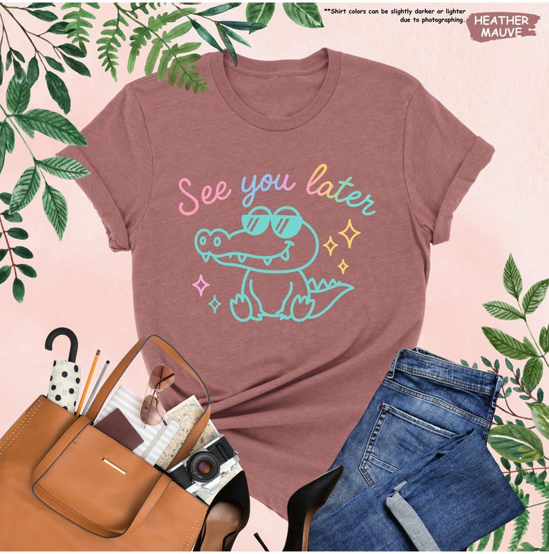 May include: Mauve t-shirt with a cartoon alligator wearing sunglasses and the phrase "See you later" in pastel colors. The shirt is paired with blue jeans, a brown purse, and black heels. The text "HEATHER MAUVE" is in the upper right corner.