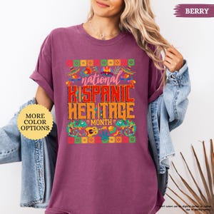 Peut inclure: T-shirt de couleur baie avec le texte "national HISPANIC HERITAGE MONTH" dans un design color&eacute;. Le t-shirt a un col rond et des manches courtes. L'image comprend &eacute;galement un bouton "MORE COLOR OPTIONS".