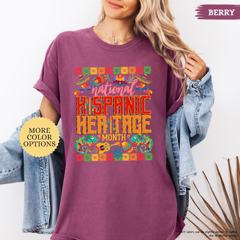 Peut inclure: T-shirt de couleur baie avec le texte "national HISPANIC HERITAGE MONTH" dans un design color&eacute;. Le t-shirt a un col rond et des manches courtes. L'image comprend &eacute;galement un bouton "MORE COLOR OPTIONS".