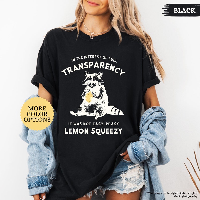 May include: Black t-shirt with a raccoon graphic and the text "In the interest of full transparency it was not easy peasy lemon squeezy".