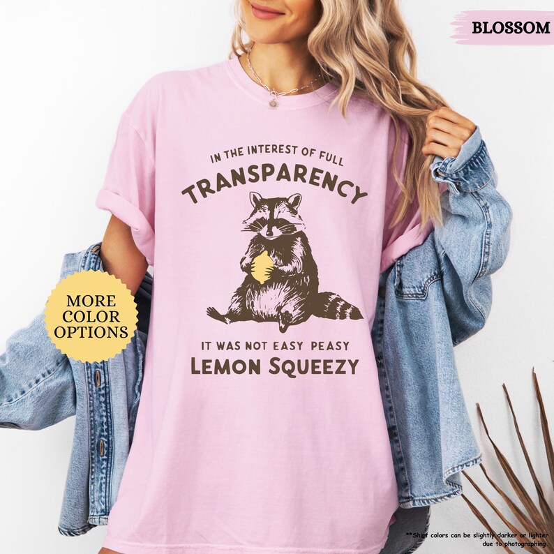 May include: Pink t-shirt with a raccoon graphic and the text "In the interest of full transparency, it was not easy peasy lemon squeezy".