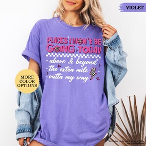 May include: A violet-colored t-shirt with the text "PLACES I WON'T BE GOING TODAY" in pink and white. The shirt also features the phrases "above & beyond", "the extra mile", and "outta my way". The shirt has a relaxed fit.