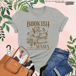 May include: Athletic heather gray t-shirt with a brown graphic that reads "Bookish Mama" with a stack of books, clock, and butterflies. The text "So many books so little time" is below the graphic. Rolled sleeves and a crew neck.
