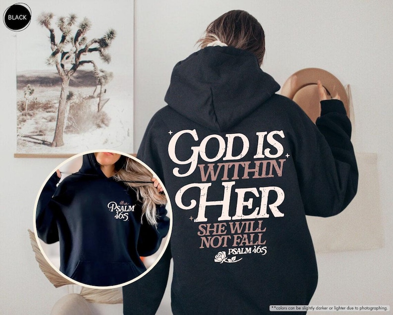 Puede incluir: Sudadera con capucha negra con el texto "GOD IS WITHIN HER SHE WILL NOT FALL PSALM 46:5" en letras blancas y malva. Una imagen m&aacute;s peque&ntilde;a muestra una sudadera con capucha azul marino con "PSALM 46:5" impreso.