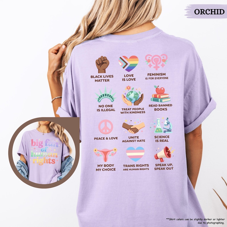 May include: Orchid-colored t-shirt with various social justice graphics and text. The shirt features phrases like "Black Lives Matter," "Love is Love," and "Feminism is for Everyone." Additional graphics include a rainbow heart, a globe, and a peace sign.