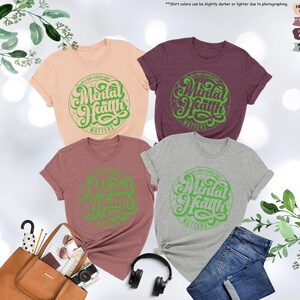 May include: Four t-shirts in different colors with the text "All Day Every Day Mental Health Matters" in a green circle on the front.