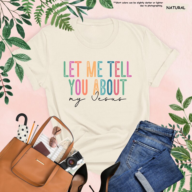 May include: A beige t-shirt with the text "LET ME TELL YOU ABOUT my Jesus" in rainbow colors. The text is in a retro font style.