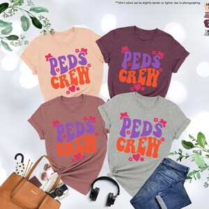May include: Four t-shirts with the text "PEDS CREW" in a retro font. The shirts are in different colors: peach, mauve, maroon, and heather grey.