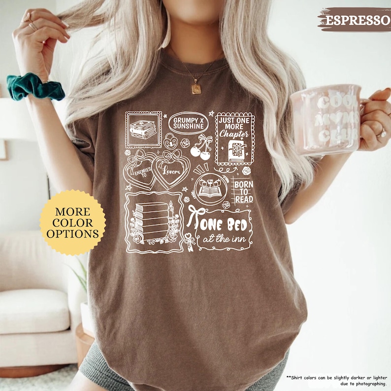 Puede incluir: Camiseta color espresso con un dise&ntilde;o gr&aacute;fico blanco que presenta libros, corazones y el texto "Grumpy x Sunshine", "Just One More Chapter", "Born to Read" y "One Bed at the Inn". Una pegatina redonda dice "More Color Options".