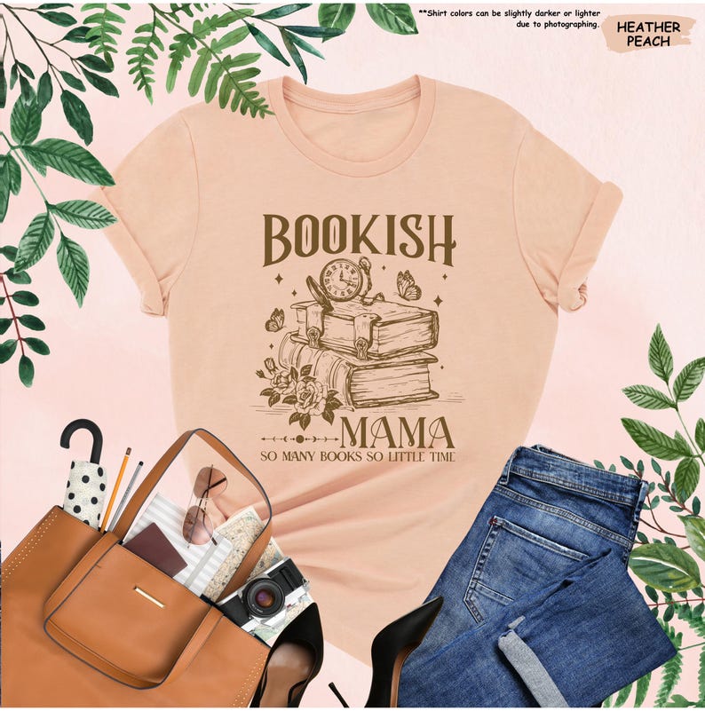 May include: A heather peach-colored t-shirt with the words "BOOKISH MAMA" and the phrase "SO MANY BOOKS SO LITTLE TIME" printed on it. The graphic includes a stack of books, a clock, and butterflies. The shirt is paired with blue jeans and a brown tote bag.